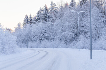 Winter evening forest with road covered with snow