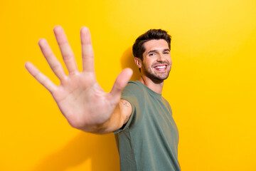 Photo of friendly good mood man with bristle dressed khaki t-shirt giving you highfive isolated on vibrant yellow color background © deagreez