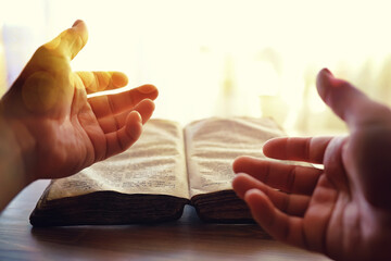 Praying with hand on bible black background. An old book with yellowed pages. Second-hand books.