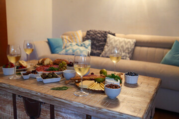 Dinner with snacks and wineglasses on table in living room