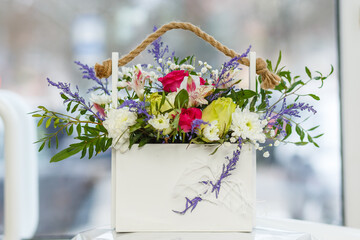 Bouquet of flowers: roses, daisies and peonies in a wooden box.