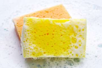 Cleaning sponge in foam of dishwashing liquid. Washing dishes concept