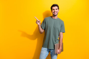 Photo of toothy beaming man dressed khaki t-shirt hold laptop indicating at offer empty space...