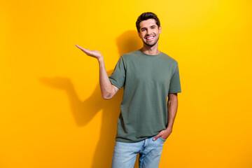 Photo of cheerful cool man with bristle dressed khaki t-shirt palm presenting product empty space...