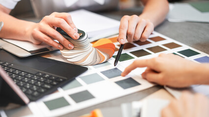Close up hand choosing color from color sample swatch. The designer works with the customer and...