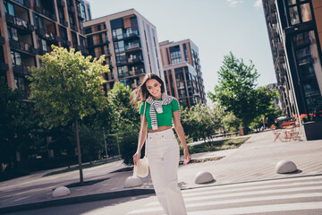 Photo of dreamy young charming woman smile wear green t shirt white pants looking asphalt she crosswalk outdoors residential complex