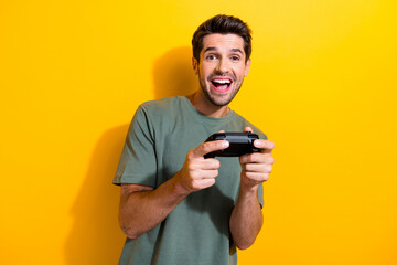 Photo of overjoyed funky man dressed khaki t-shirt holding playstation joystick play video game...