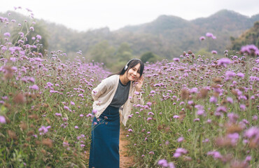 Portrait of young adult asian woman relax in wild flower listen music with headphone and dancing in self mood