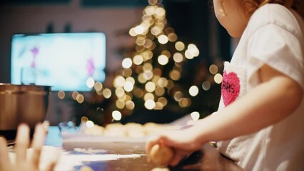 Little girls make cookies and watch TV at home on the Christmas or New Year Eve