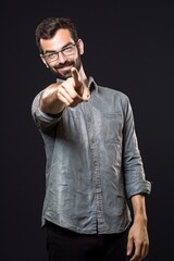 Fototapeta premium Young man pointing to the front isolated on dark background.