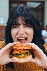 close-up vertical image of hungry caucasian woman eating hamburger