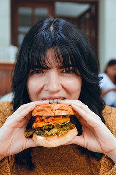close-up vertical image of hungry caucasian woman eating hamburger