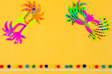 Two colorful masks side by side on a yellow background decorated with colorful streamers
