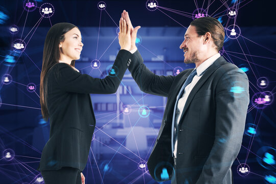 Side view of happy businessman and woman hi-fiving with connected digital people team icons on dark blurry purple office interior background. Digital network, community and social media concept. - Powered by Adobe