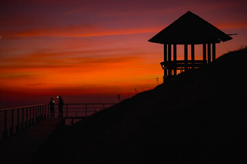 Silhouette pavilion by the hill during the dusk sky with the moon and tourists camping on the Doi Pui Co mountain in Thailand. Scenic landscape, Hiking trails, and camping in Northern Thailand
