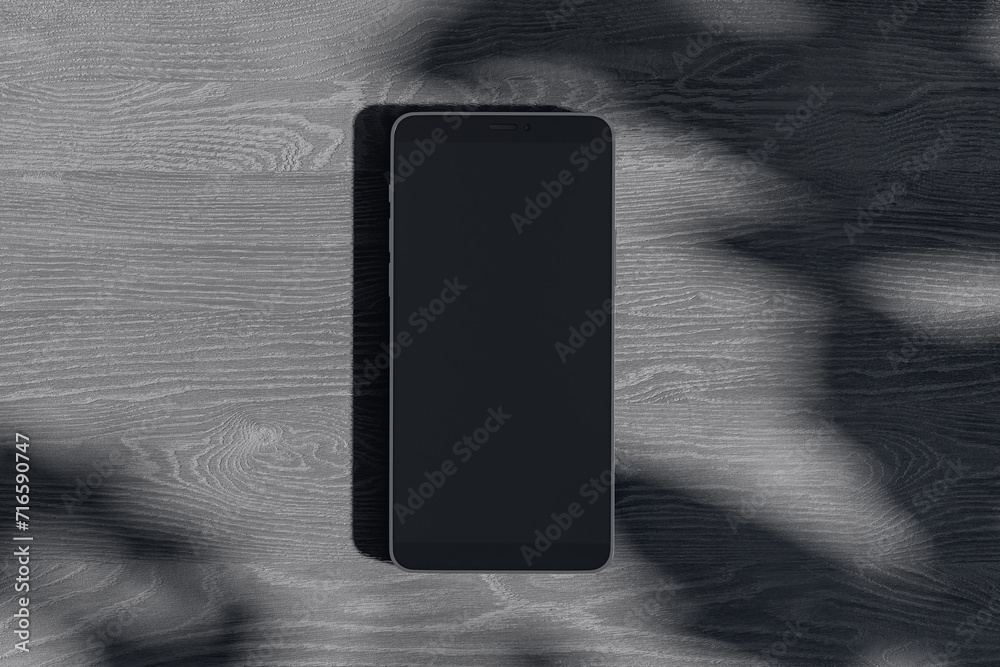 Poster Close up of empty smartphone on dark wooden surface with leaf shadows. Presentation concept. Mock up, 3D Rendering.