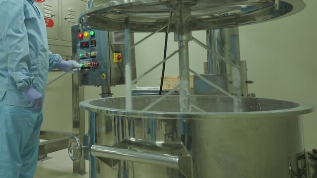 Chemist in protective clothing working with a large planetary mixer in the laboratory.
