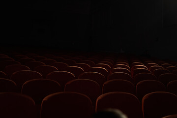 Close up of orange, red seats in dark empty cinema hall with copy space. Background with rows of...