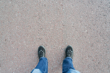 Point of view with sneaker shoes standing on grey road