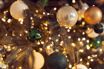 Close up of white, black, green and golden Christmas balls, garlands, string light handing on...