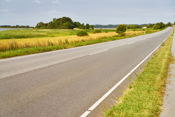 Road with two lanes as straight line through farmland