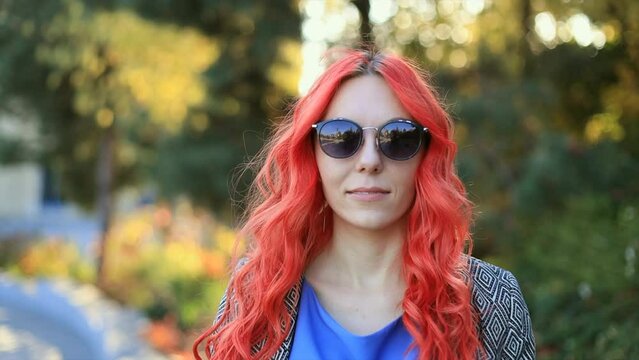 Close up young red haired business and successful woman in sunglasses outdoor of the city sunset background. Camera zooming
