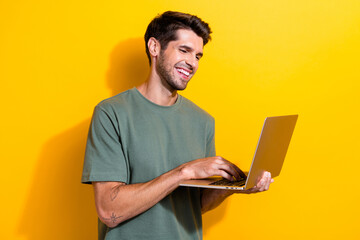 Photo of clever positive man with bristle dressed khaki t-shirt read email on laptop in arms...