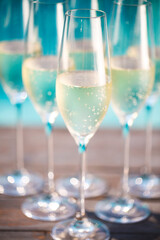 Champagne glasses on wooden background near pool