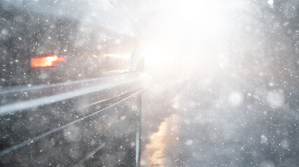 snowfall, car, background in a snowstorm with a copy of the space, the headlights of an oncoming car through a thick snowfall, winter view on the highway, headlight light