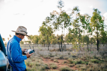 Drone operator looking at remote control in the paddock