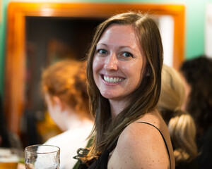 Woman with long brown hair looking into camera with glass in hand
