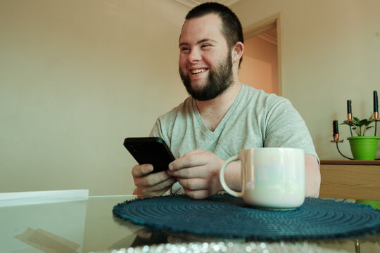 Young Man with Down Syndrome Laughing and Holding Smartphone