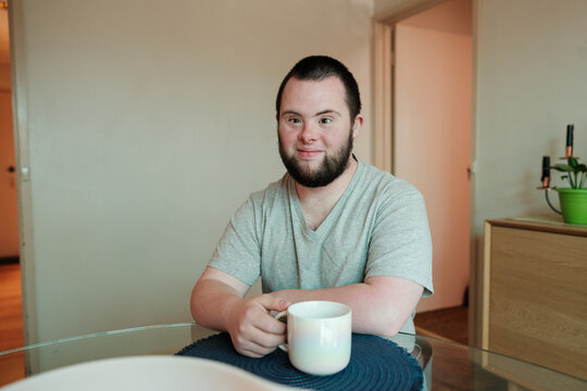 Young Man with Down Syndrome Having a Cuppa
