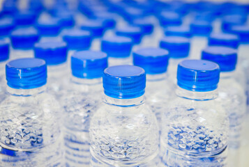 Many blue drinking water bottle caps and pure drinking water bottles in a drinking water production plant.