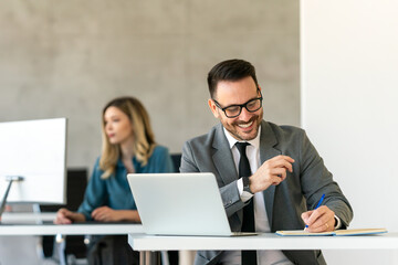 Young businessman using laptop computer in office. Manager thinks about successful financial ideas.