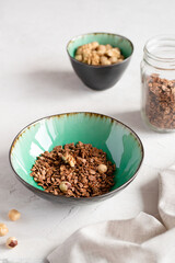 Homemade granola with nuts and chocolate in a ceramic bowl on a light concrete background. Cereals. Healthy food.