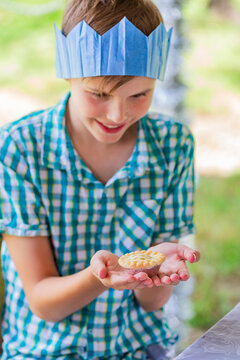 Aussie child staring hungrily at fruit mince pie in hands while wearing paper crown at Christmas