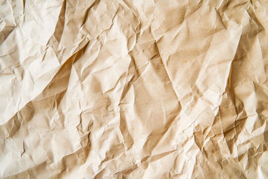 High-resolution image of crumpled ivory beige paper texture, highlighting the chaotic creases and the soft, natural color. AI generated