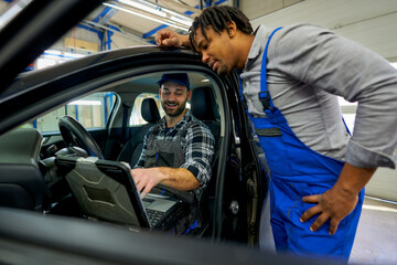 Mechanic colleagues connected the car to diagnostics. One in the driver's seat, the other outside,...