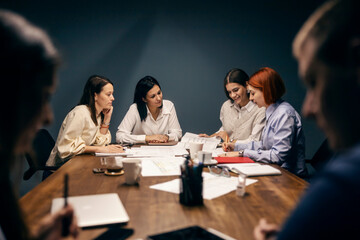 Group of businesspeople sitting at boardroom and working on documents and blueprints.
