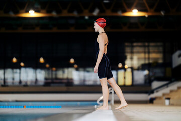 Side view of a professional swimmer standing near swimming pool.