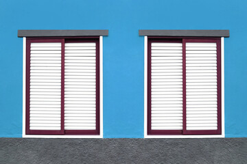 Two windows house. Closed shutters. Window shutters background. Blue home wall facade. Summer...