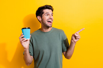 Photo of impressed man dressed khaki t-shirt holding coffee directing look at promo empty space...