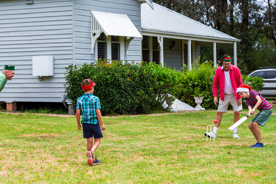 Christmastime backyard cricket game in yard of country style weatherboard home