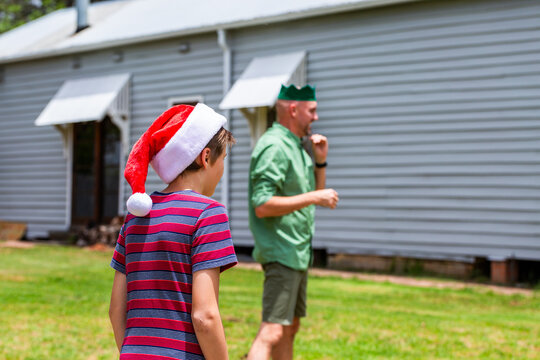 boy and dad wearing silly Christmas hats in backyard cricket game