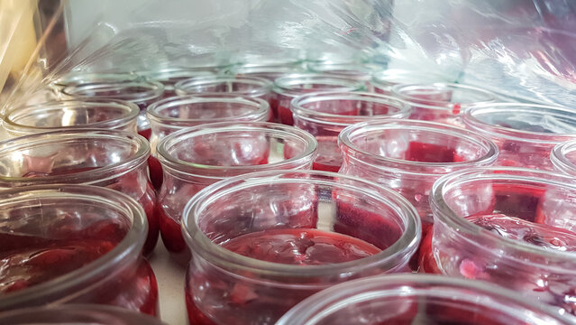Rote Grütze Dessert im Glas unter Folie im Kühlhaus