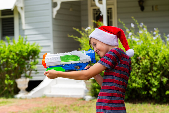 Aussie boy in Christmas Santa hat squirting water gun