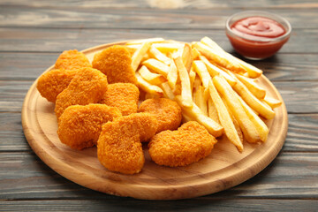 Plate of chicken nuggets with french fries and ketchup on cutting board
