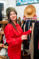 Woman trying on warm hat in a vintage clothes store