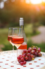 Two glasses and bottle of rose wine in autumn vineyard on marble table